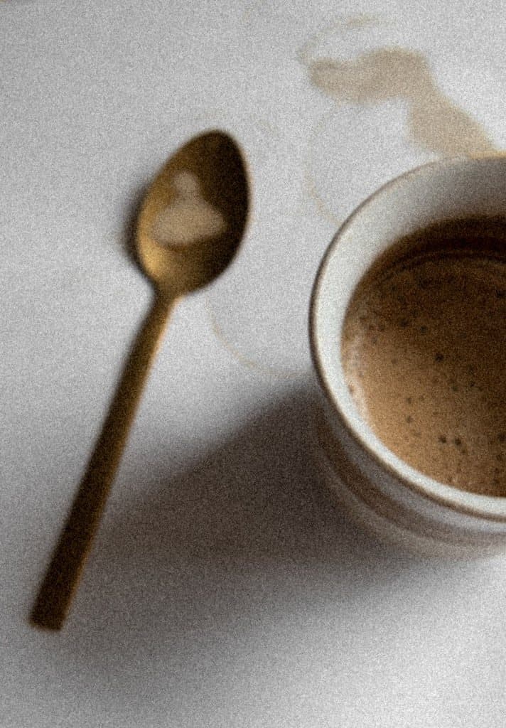 Cup of coffee with a gold spoon on a white linen table