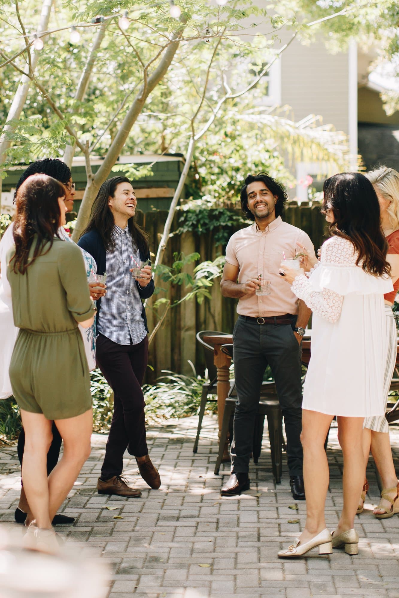 Guests chatting with drinks in a leafy brick courtyard